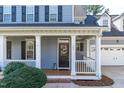 Inviting front porch with white railings and columns, leading to a black front door with wreath at 104 Stenness Ct, Apex, NC 27502