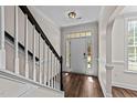 Bright entryway with hardwood floors, white trim, and a staircase with black handrail at 104 Vinewood Pl, Holly Springs, NC 27540