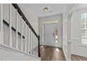 Bright foyer with hardwood floors, staircase with black railing and white door at 104 Vinewood Pl, Holly Springs, NC 27540