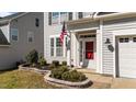 Front entrance features landscaping, an American flag, and a red front door at 104 Vinewood Pl, Holly Springs, NC 27540