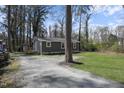 Side view of a single-story home with gray siding, white trim, wooden deck, and shed at 1208 Goldsboro Ave, Sanford, NC 27330