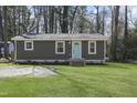Charming single-story home featuring a light-blue front door, well-manicured lawn, and mature trees at 1208 Goldsboro Ave, Sanford, NC 27330