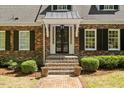 Close up of the front door of a brick house, flanked by brick steps and green shrubbery at 2140 N Lakeshore Dr, Chapel Hill, NC 27514