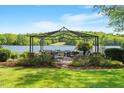 Lakeside patio featuring a metal gazebo, stone accents, and lush landscaping at 2140 N Lakeshore Dr, Chapel Hill, NC 27514