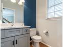 Cozy bathroom with modern gray vanity, white quartz countertop, blue accent wall, and hardwood floors at 2301 Lemuel Dr, Raleigh, NC 27615