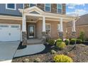 Inviting front porch featuring classic brick columns, a cozy seating area, and beautifully landscaped surroundings at 234 Macallan Dr, Burlington, NC 27215
