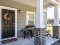 Inviting front porch with brick-based columns, comfortable seating, and a festive wreath on the door at 2575 Sheriff Watson Rd, Sanford, NC 27332