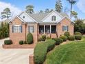 Beautiful brick home featuring a charming front porch with rocking chairs and lush landscaping at 3204 Cobblestone Ct, Raleigh, NC 27607