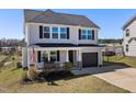 Charming two-story home featuring gray siding, a one-car garage, and a welcoming front porch with an American flag at 38 Winter Red Way, Benson, NC 27504