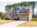 Charming two-story home featuring a covered front porch, a side-entry garage, and mature trees at 50 Lockamy Ln, Youngsville, NC 27596