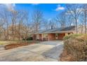 A single story home featuring a paved driveway leading to a charming brick home in a wooded setting at 501 Orange High School Rd, Hillsborough, NC 27278