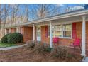 Inviting covered front porch with red chairs, complemented by red shutters and landscaped greenery at 501 Orange High School Rd, Hillsborough, NC 27278