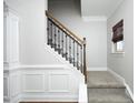 Elegant staircase with carpeted steps, white wainscoting, and wrought iron spindles at 5204 Sapphire Springs Dr, Knightdale, NC 27545