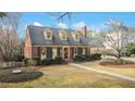 Quaint brick home featuring dormer windows, lush lawn, and a winding walkway at 527 N Main St, Wake Forest, NC 27587