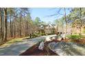 Scenic view of a stone and siding home with a long driveway, surrounded by mature trees and natural landscaping at 5640 Bella Terra Ct, Wake Forest, NC 27587