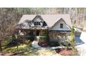 Aerial view of a stone and siding home featuring a covered front porch, well-maintained landscaping, and a wooded lot at 5640 Bella Terra Ct, Wake Forest, NC 27587