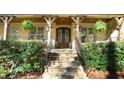 Inviting front porch with stone steps, wooden columns, hanging ferns, and a wooden ceiling at 5640 Bella Terra Ct, Wake Forest, NC 27587