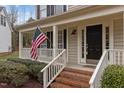 Inviting covered front porch with brick steps and white railing, decorated with an American flag for a patriotic welcome at 733 Hillsford Ln, Apex, NC 27502