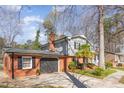 View of the home's garage, complemented by brickwork and verdant landscaping at 817 Roanoke Dr, Cary, NC 27513