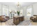 Well-lit office features hardwood floors, decorative chandelier, and two large windows at 2720 Stratford Hall Dr, Raleigh, NC 27614