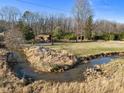 Picturesque aerial view showcases a home with a creek bordering the property and lush greenery at 3010 University Station Rd, Durham, NC 27705