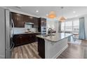 Modern kitchen features dark cabinets, granite countertops, stainless steel appliances, and an island with pendant lighting at 308 Masden Rd, Holly Springs, NC 27540