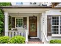 Inviting front porch with wooden door, brick steps, and white railing with black shutters on a white painted brick home at 3421 Griffice Mill Rd, Raleigh, NC 27610