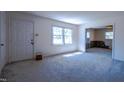 Bright, carpeted living room with a large window and an open doorway to the kitchen at 510 Corrida Ave, Durham, NC 27704