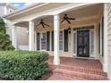 Inviting front porch with brick flooring, white columns, ceiling fans, and an elegant front door at 5102 Highcroft Dr, Cary, NC 27519