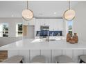 Modern kitchen with white cabinets, a sleek island with bar seating, and blue backsplash offers style and functionality at 517 Coleman St, Raleigh, NC 27610