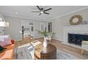 Bright living room features hardwood floors, a fireplace, modern fan, and view to a kitchen at 518 W Chisholm St, Sanford, NC 27330