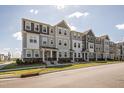 Beautiful three-story townhomes featuring varied neutral colors and well-maintained lawns on a sunny day at 6434 Astor Elgin St, Raleigh, NC 27616