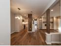 Open-concept living room features hardwood floors, modern lighting, and access to a stylish kitchen with stainless appliances at 700 Bishops Park Dr # 205, Raleigh, NC 27605