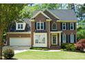 Charming brick home with lush green lawn, mature trees, and two-car garage at 102 Caymus Ct, Cary, NC 27519