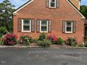 Side view of the brick exterior with mature landscaping, green bushes, and colorful flowering shrubs at 132 Lord Ashley Rd, Raleigh, NC 27610
