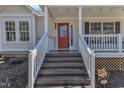 Inviting front porch features stairs, white railings, and a striking red door at 1384 Sims Bridge Rd, Kittrell, NC 27544