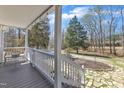 An exterior view of the porch that highlights wood flooring, white railing and a natural landscape at 1384 Sims Bridge Rd, Kittrell, NC 27544