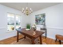Bright office space with a wooden desk, chandelier, and large window overlooking the yard at 213 Yellow Poplar Ave, Wake Forest, NC 27587
