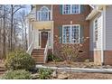 Inviting entrance featuring a covered porch, brick steps, and a solid wood front door with glass accents at 2325 Old Oak Pl, Hillsborough, NC 27278