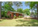 Well-maintained brick home featuring a covered carport and a fenced backyard, surrounded by mature trees at 2968 Tram Rd, Fuquay Varina, NC 27526