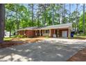 Brick home featuring a covered carport with an attached storage area and a long concrete driveway at 2968 Tram Rd, Fuquay Varina, NC 27526