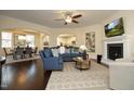 Open-concept living room featuring a fireplace, ceiling fan, and dark hardwood flooring at 5421 Downton Grove Ct, Fuquay Varina, NC 27526