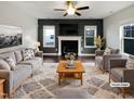 A staged living room with a fireplace, neutral furniture, and large windows at 69 Azul Dr, Clayton, NC 27520