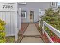 Exterior of home entrance with gray siding, brick pathway and lush greenery at 7305 Sandy Creek Dr, Raleigh, NC 27615
