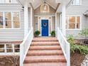 Inviting front entrance with brick steps, white railings, and a blue front door adorned with a floral wreath at 104 Manchester Pl, Chapel Hill, NC 27516