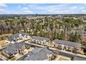 Beautiful aerial view of townhome community with mature trees and a view of the city skyline on a sunny day at 138 Tressel Way, Durham, NC 27707