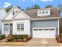 Beautiful home exterior featuring a light-colored facade, white garage doors, and manicured bushes at 1564 Highpoint St, Wake Forest, NC 27587