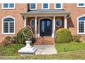 Elegant entryway with brick steps and decorative wrought-iron door with manicured landscaping at 212 Whirlaway Ln, Chapel Hill, NC 27516