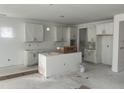 Unfinished kitchen featuring white cabinets, a central island, and awaiting appliances, offering a customizable space at 230 Tidal Pool Way, Cary, NC 27519