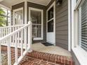 Inviting covered front porch with white railings and a brick base, creating a warm welcome at 27 Kings Mount Ct, Durham, NC 27713